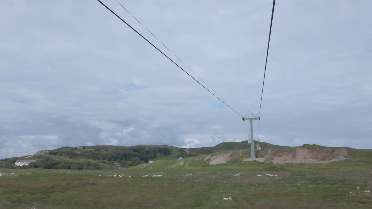 Cabinovia per il trasporto turistico panoramico che sorvola un pittoresco pendio montano in una valle, con ripresa in picchiata.