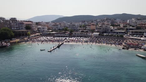 Beach-packed-with-tourists-in-popular-coastal-town-Ksamil,-Albania