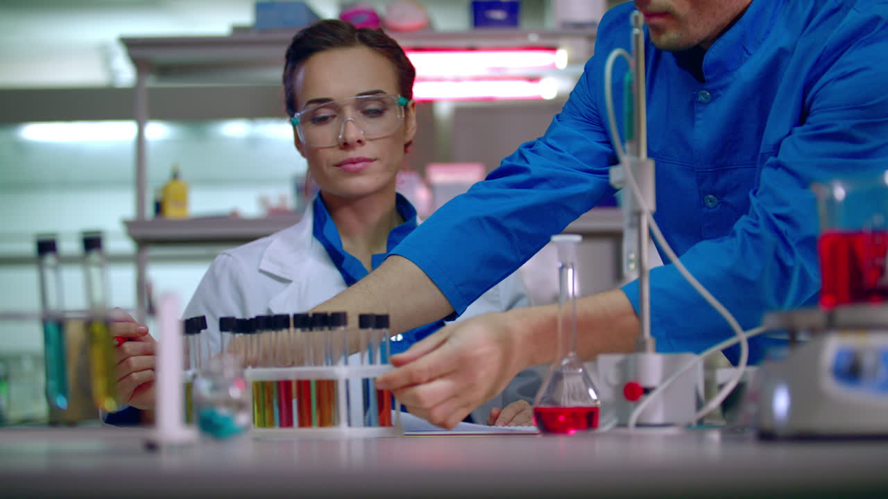 mujer química escribiendo datos de investigación en el laboratorio. trabajador de laboratorio recoge el estante del tubo de ensayo