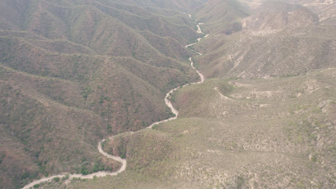 vista aérea del valle que revela montañas y cañón con un camino que conduce a un camino desconocido