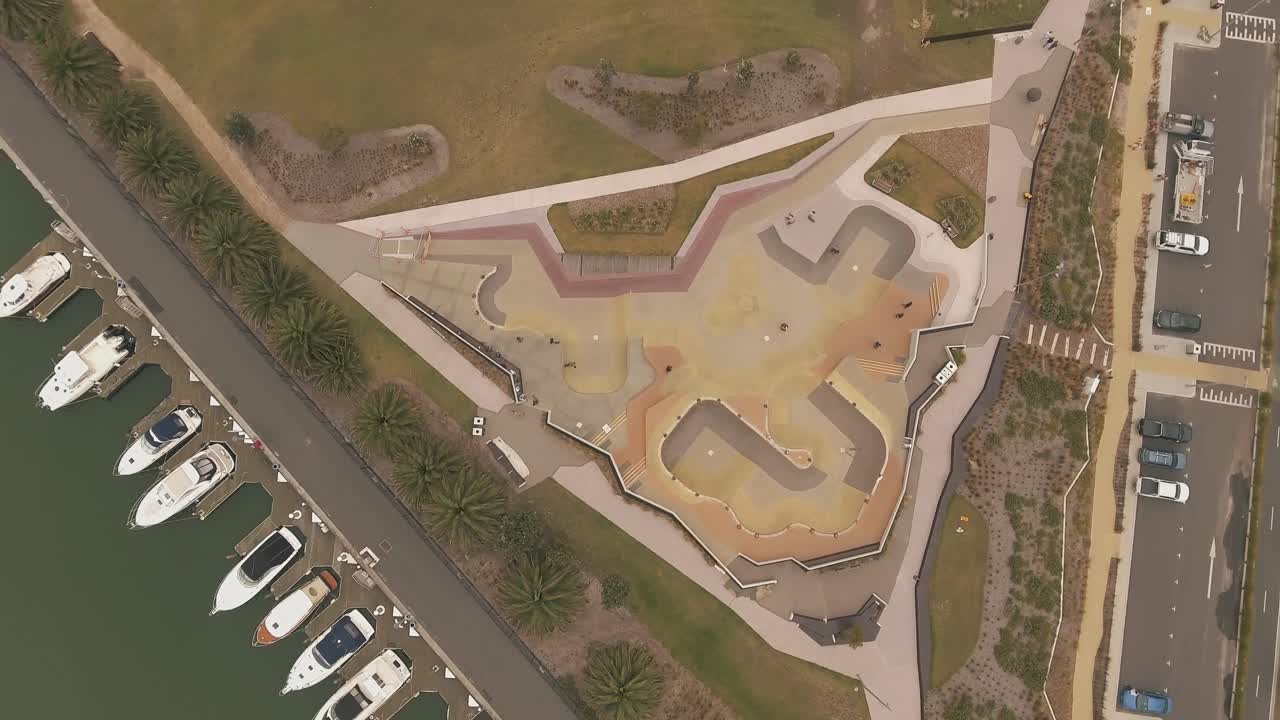 antena de drones girando sobre el parque de patinaje con palmeras y botes en st kilda melbourne