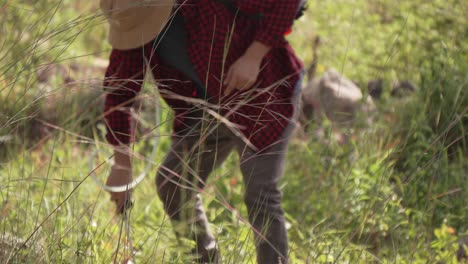 Medium-shot-of-man-working-with-backpack-sprayer,-he-wears-a-red-shirt-and-a-hat