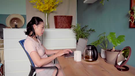 asian woman reading document on laptop and working at home