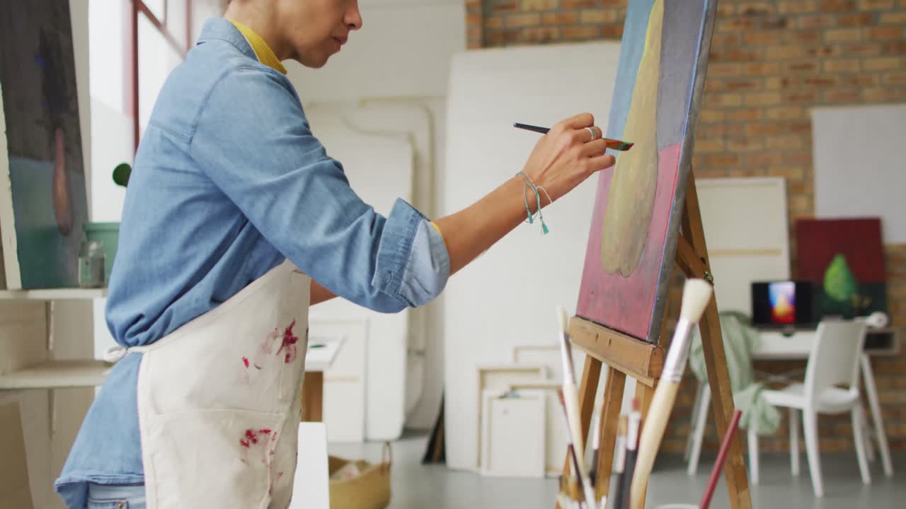 video de una artista biracial pintando en un estudio
