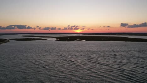 Aerial-hyperlapse-over-campsite-hotels-on-beach-shores-of-Chincoteague-Virginia-as-sun-sets-below-horizon