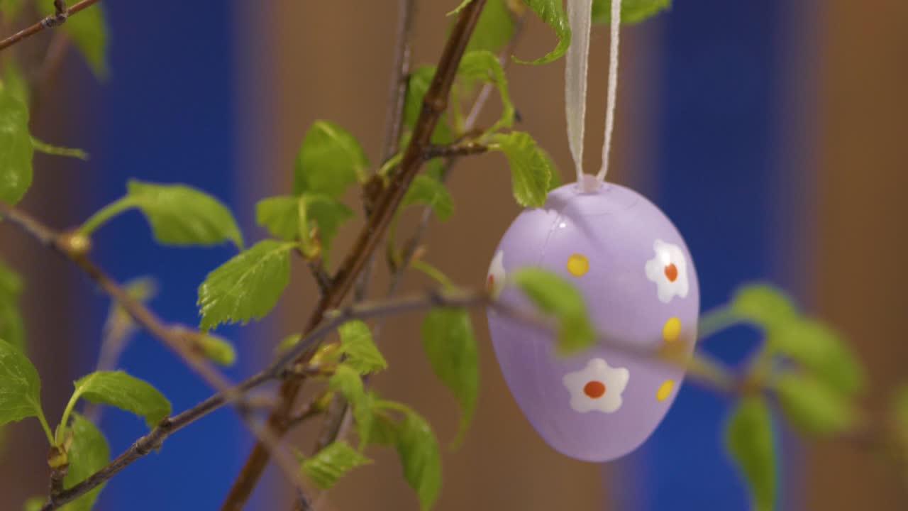 An artificial Easter egg hung on a birch branch in a vase