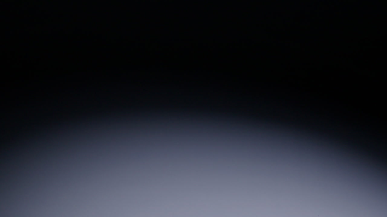 Slow-motion wide shot of blue role-playing die falling into middle of screen and rolling out of shot to screen right