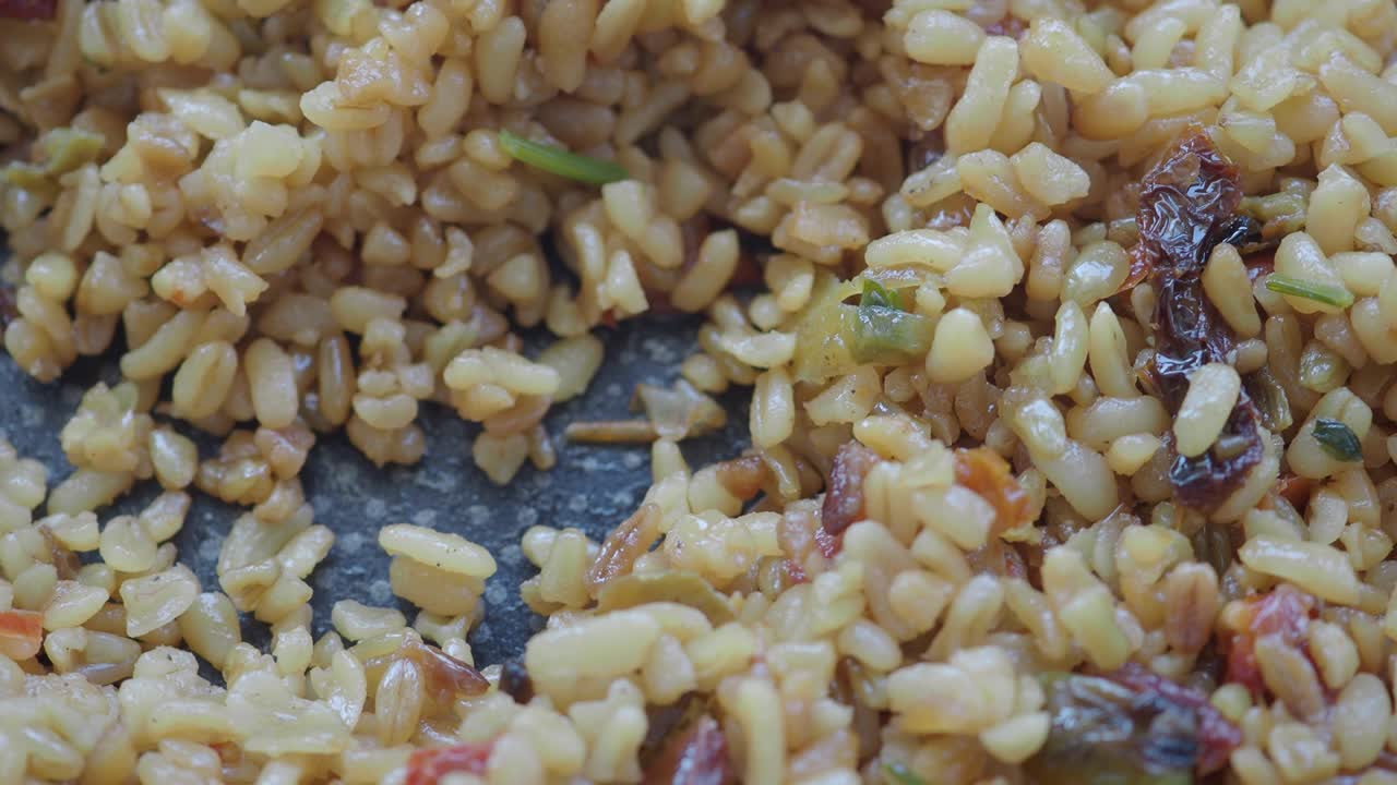 Primo piano di bulgur cotto con pomodori secchi ed erbe aromatiche