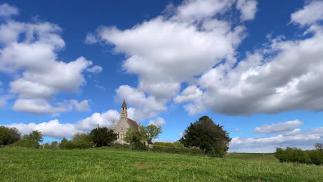 nubes blancas y esponjosas cumulus pasando sobre la pequeña iglesia de st. en la aldea de weethley, warwickshire, inglaterra en un video timelapse en un soleado día de primavera