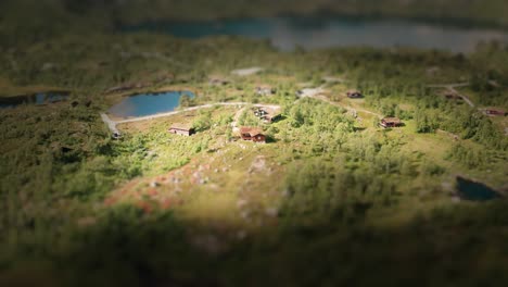 a miniature norwegian village seen from bird's eye view located on countless slopes covered with coniferous trees and stones