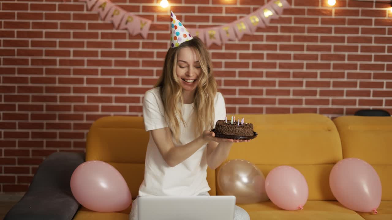 chica emocionada celebra su cumpleaños en línea por webcam sosteniendo pastel con velas