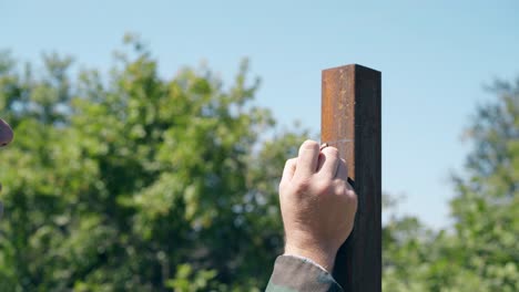 close view builder makes mark on pole against trees and sky