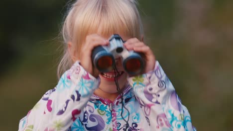 a cheerful child looks through binoculars