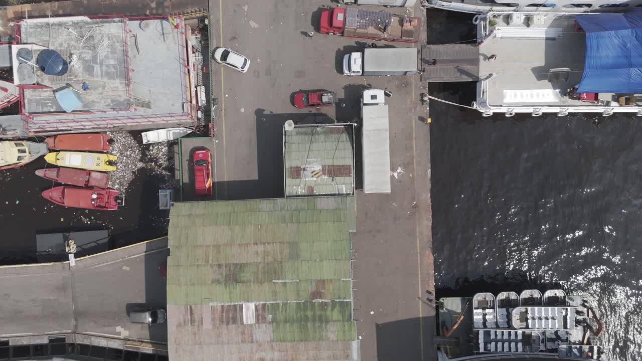 Manaus city harbour on the Rio Negro, Brazil, showing dock area, warehouse roofs and port activity at an Amazon River terminal, top-down aerial panning view
