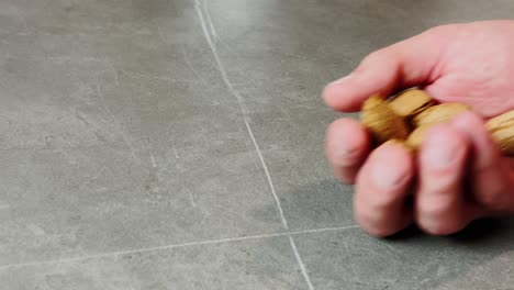 a hand holding a small pile of whole almonds in their shells, highlighting the natural texture and nutritious qualities of this healthy snack.