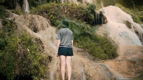 caucasian girl standing at waterfall in asia