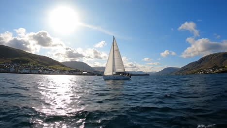 sailboat on a sunny day in a scenic fjord with coastal village