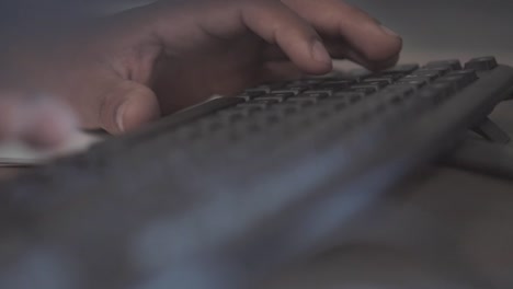 Black male hands typing on a black keyboard