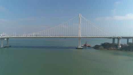 Toma-Aérea-De-Vehículos-Moviéndose-En-El-Puente-De-La-Bahía-De-San-Francisco–oakland-Con-La-Ciudad-Al-Fondo