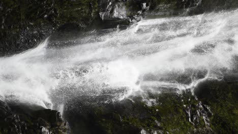 Ein-Vertikales-Video-Eines-Wasserfalls-über-Moosigen-Felsen,-Der-Nach-Unten-Schwenkt