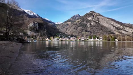 Perspectiva-De-Terreno-Bajo-De-Un-Pueblo-De-Montaña-Al-Fondo-Con-Olas-De-Fantasía-En-El-Lago-En-Primer-Plano-Con-Un-Destino-De-Vacaciones-Celestial