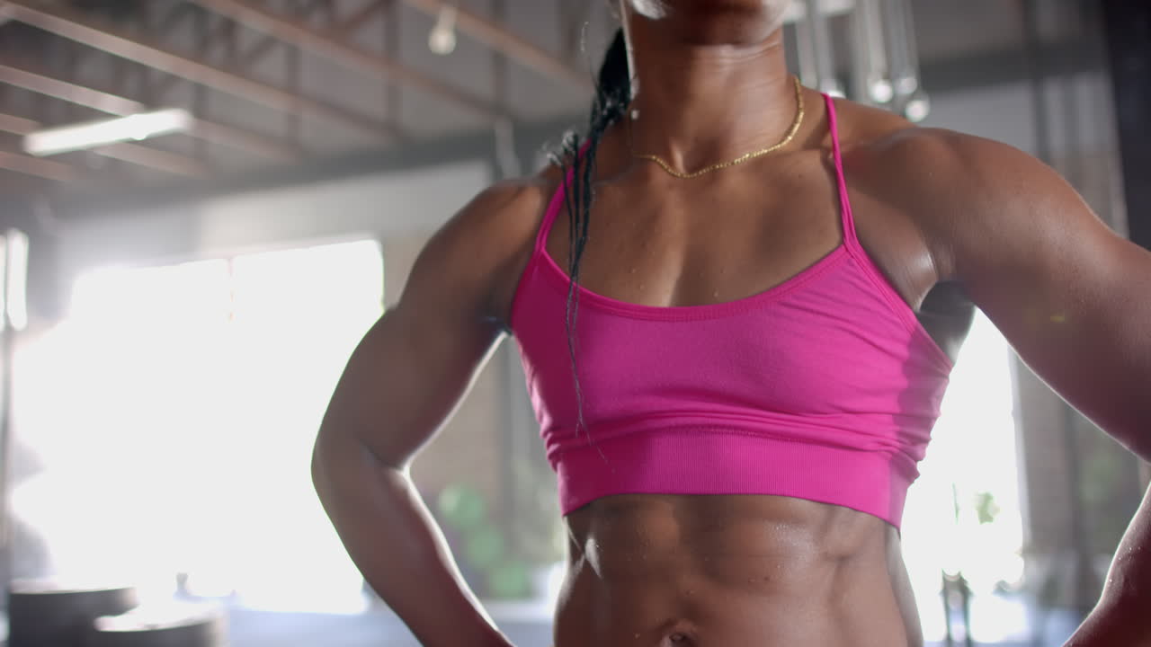 Wearing pink sports bra, woman showing toned abs and muscles in gym, copy space