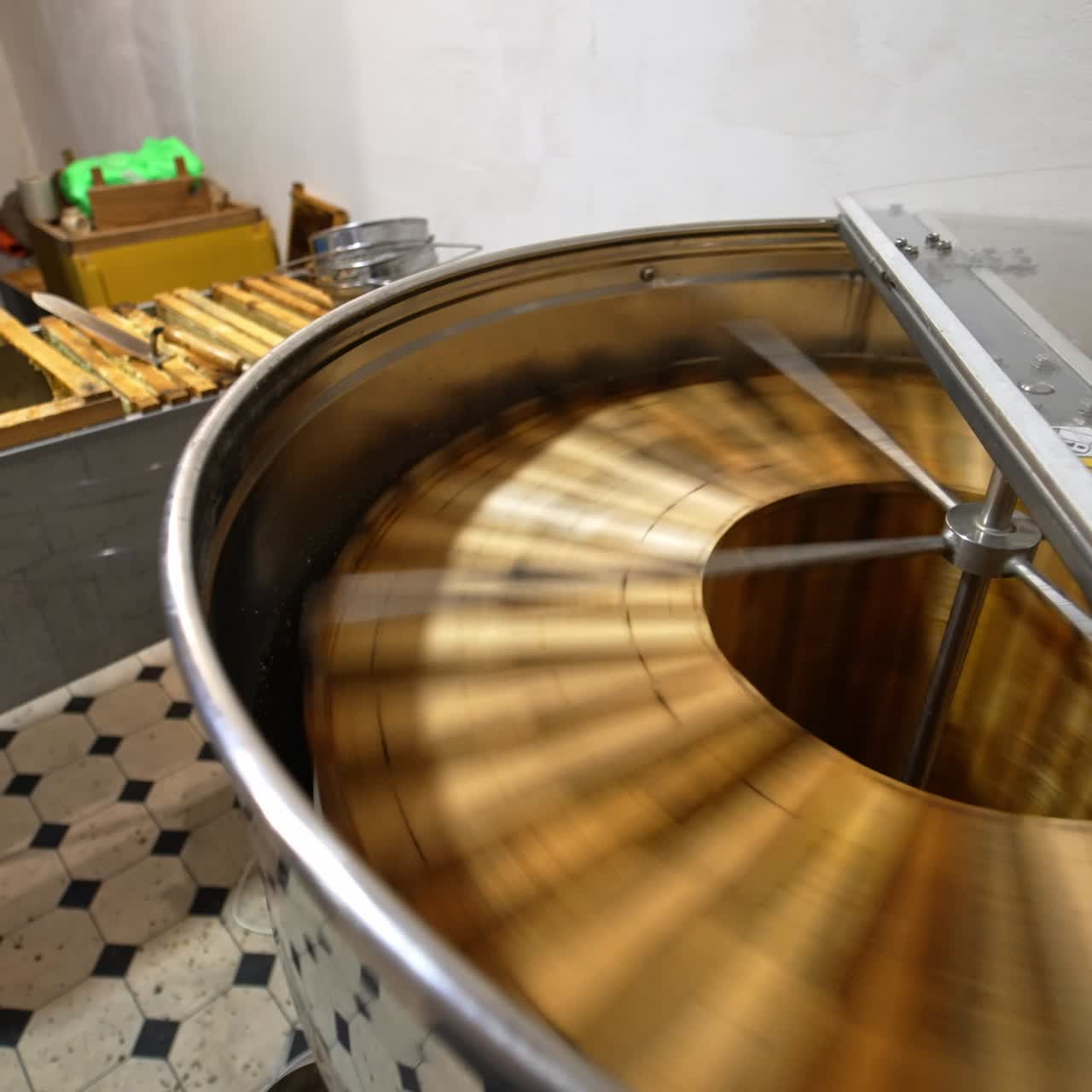 Rotating mechanism working in the centrifuge machine at apiary. Metal box full of frames standing beside. Process of organic honey extraction