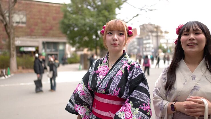 Due donne in yukata tradizionali passeggiano in un parco pubblico vicino a un santuario shintoista.