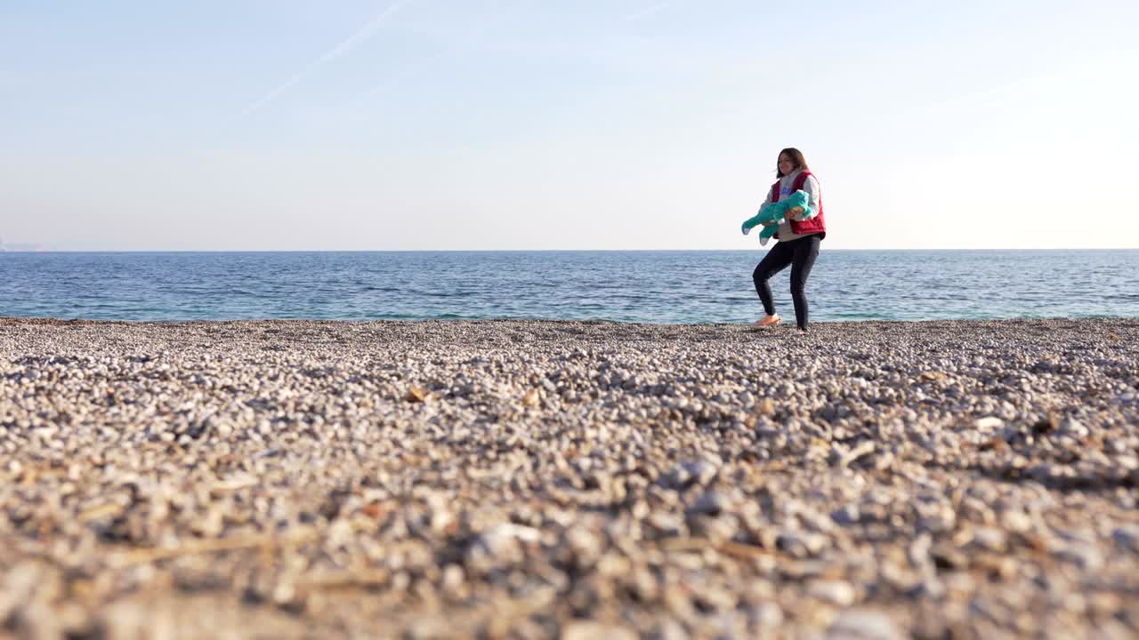 작은 아기를 들고 있는 어머니가 해변에서 놀고 있습니다.