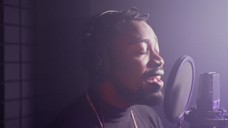 hombre cantando en un micrófono en un estudio de grabación