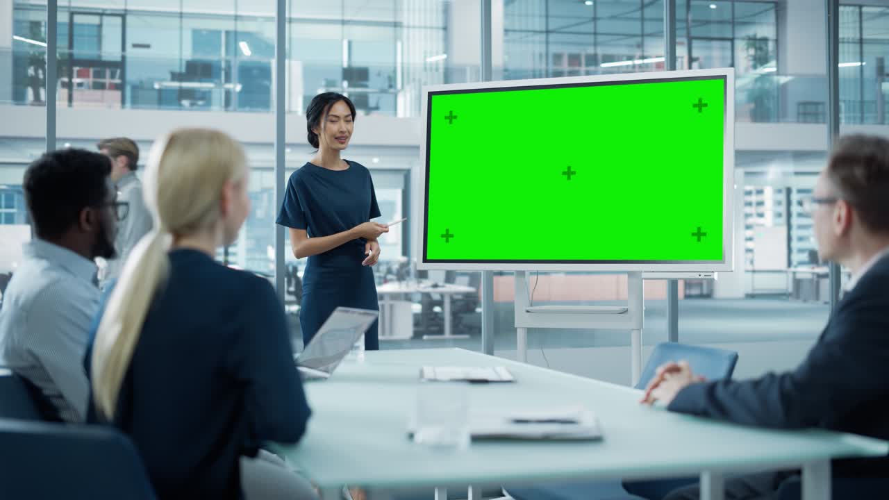 Female Operations Manager Holds Meeting Presentation for a Team of Economists. Asian Woman Uses Digital Whiteboard with Horizontal Green Screen Mock Up Display. People Work in Business Office.