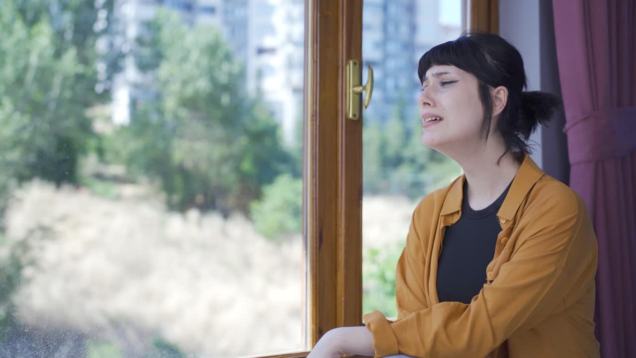 집에서 혼자 젊은 여성이 울고 있습니다.