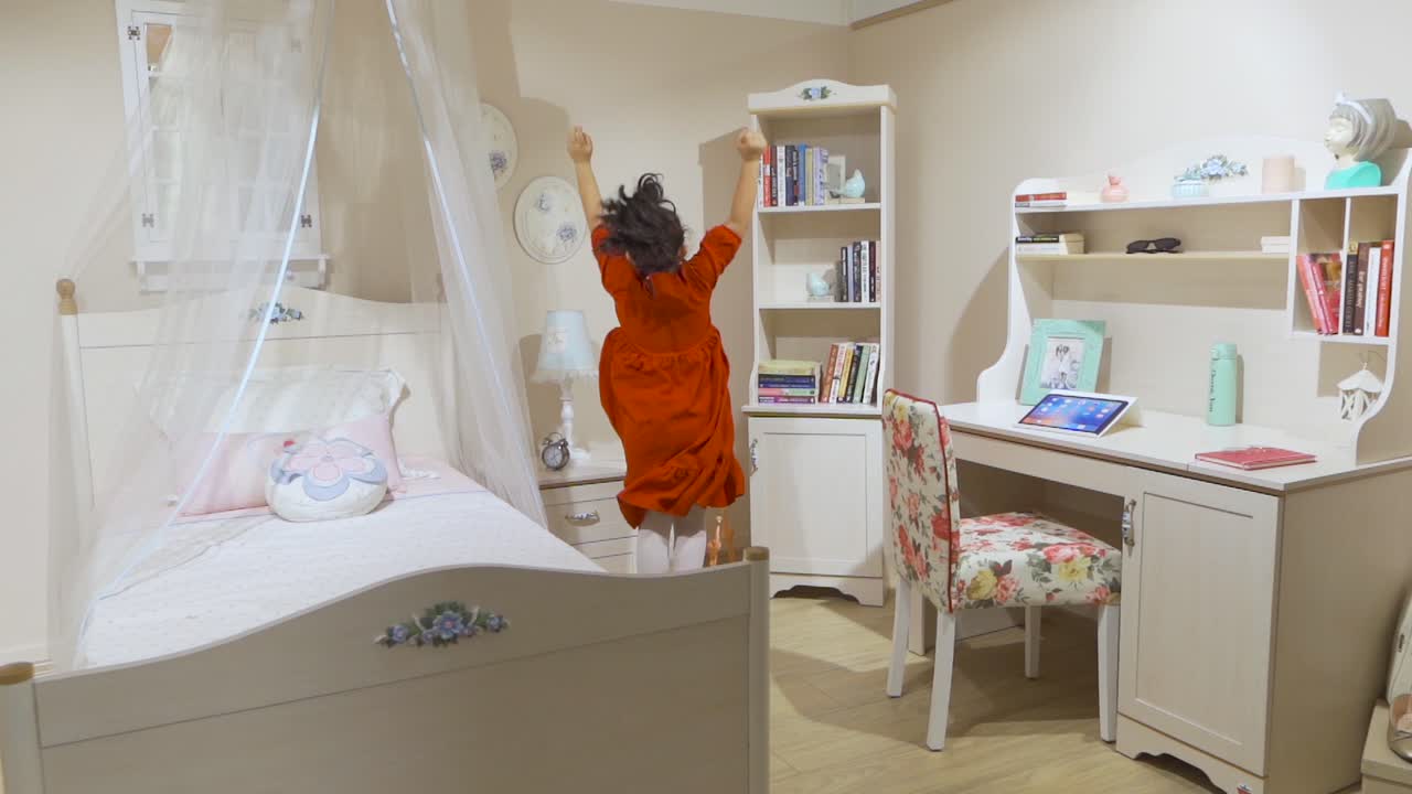 Cute little girl jumping in the air in her room.