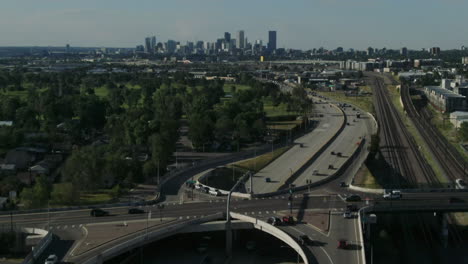 Drone-following-tilt-shot-of-cars-driving-over-the-highway-towards-the-skyline-of-Denver