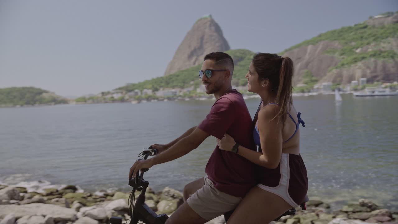 A couple enjoying an electric bike ride by the scenic bay with mountains