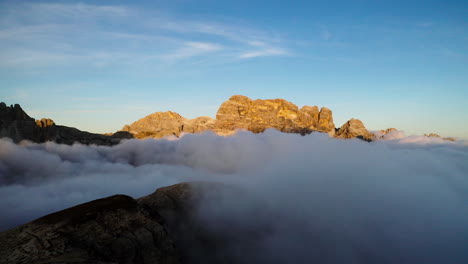 sunlit south tyrol mountains surrounded by ethereal clouds aerial forward view over rocky dolomites ant sunrise