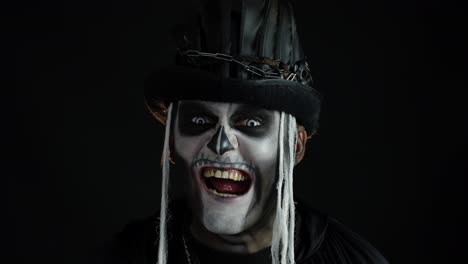 Man-with-skeleton-makeup-trying-to-scare,-opening-his-mouth-and-showing-dirty-black-teeth-and-tongue