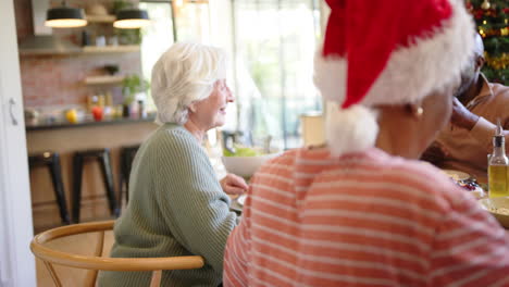 Glückliche-ältere-Kaukasische-Frau-Am-Weihnachtstisch-Mit-Verschiedenen-Freunden,-Zeitlupe