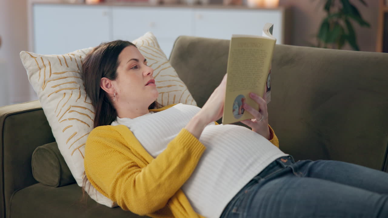 Pregnant woman reading on sofa