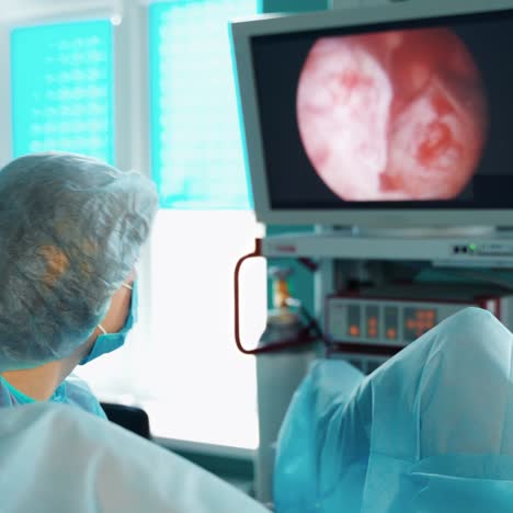 doctor looks on medical monitor. female specialist in medical uniform making operation to a patient and observes detail organs of a patient on the screen. modern medicine.