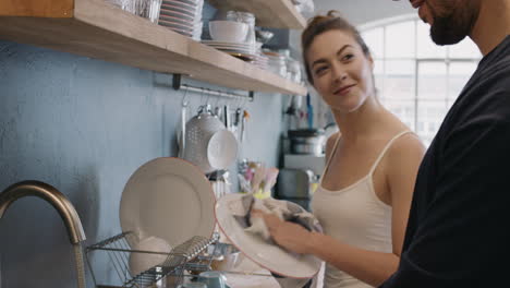 Newly-wed-in-love-couple-at-home-washing-dishes-wearing-pajamas-having-fun