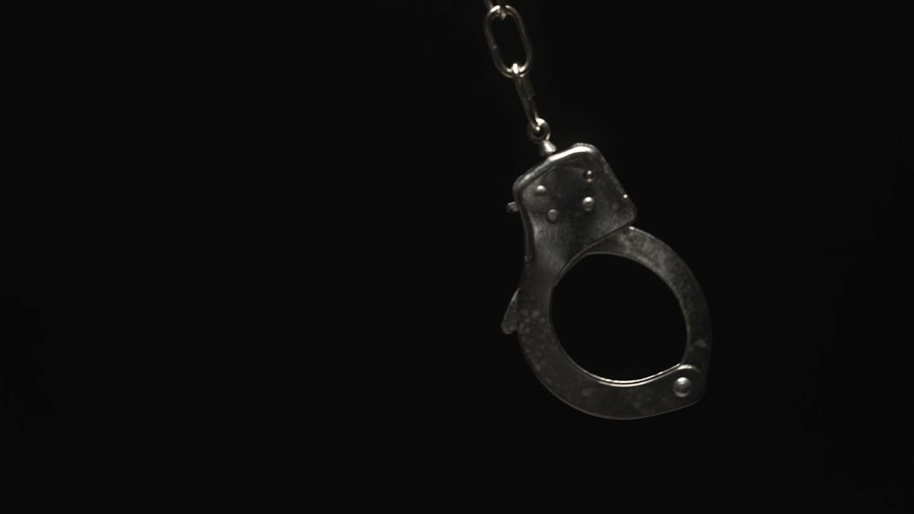 Close-up of Handcuff Swinging in Black Background