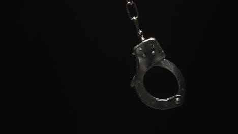 close-up of handcuff swinging in black background