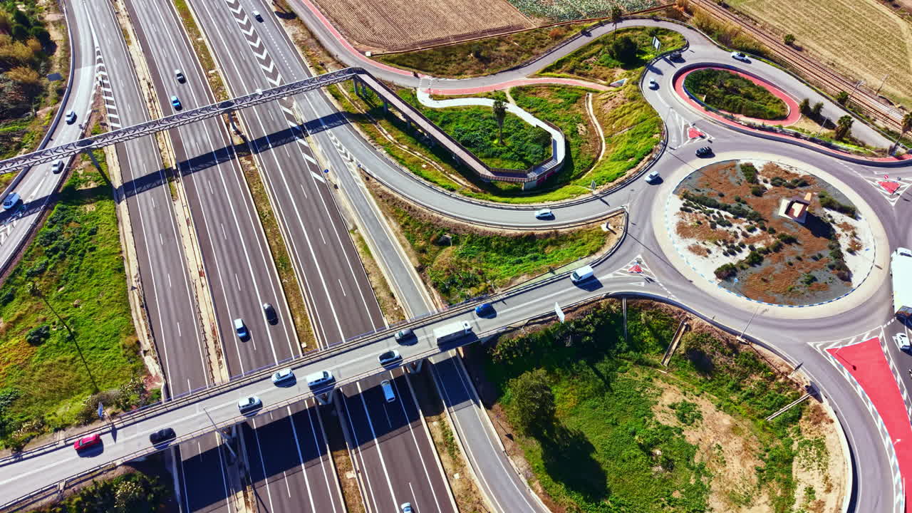 Traffic flows through roads and roundabouts in a busy area during daylight, capturing the movement of vehicles and infrastructure