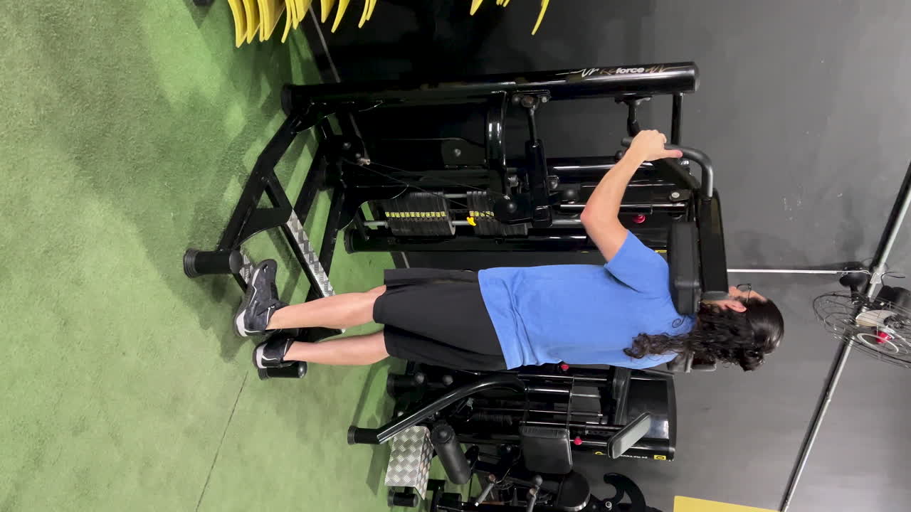 Latin man with long hair and beard doing standing calf exercises on gym equipment