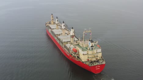 international cargo ship, empty barge with no shipments sailing slowly on the sea, close to port lumut, manjung, perak, malaysia, southeast asia, aerial drone shot.