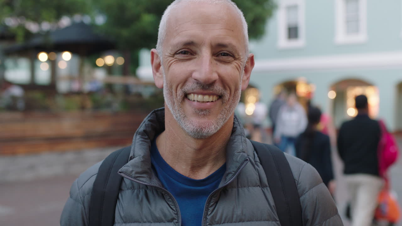 close up portrait of mature attractive caucasian tourist man looking at camera smiling urban background