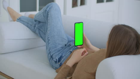 young girl is holding smartphone with green screen at evening time. smartphone in hand static footage with little hand moves. indicators on screen to track movement