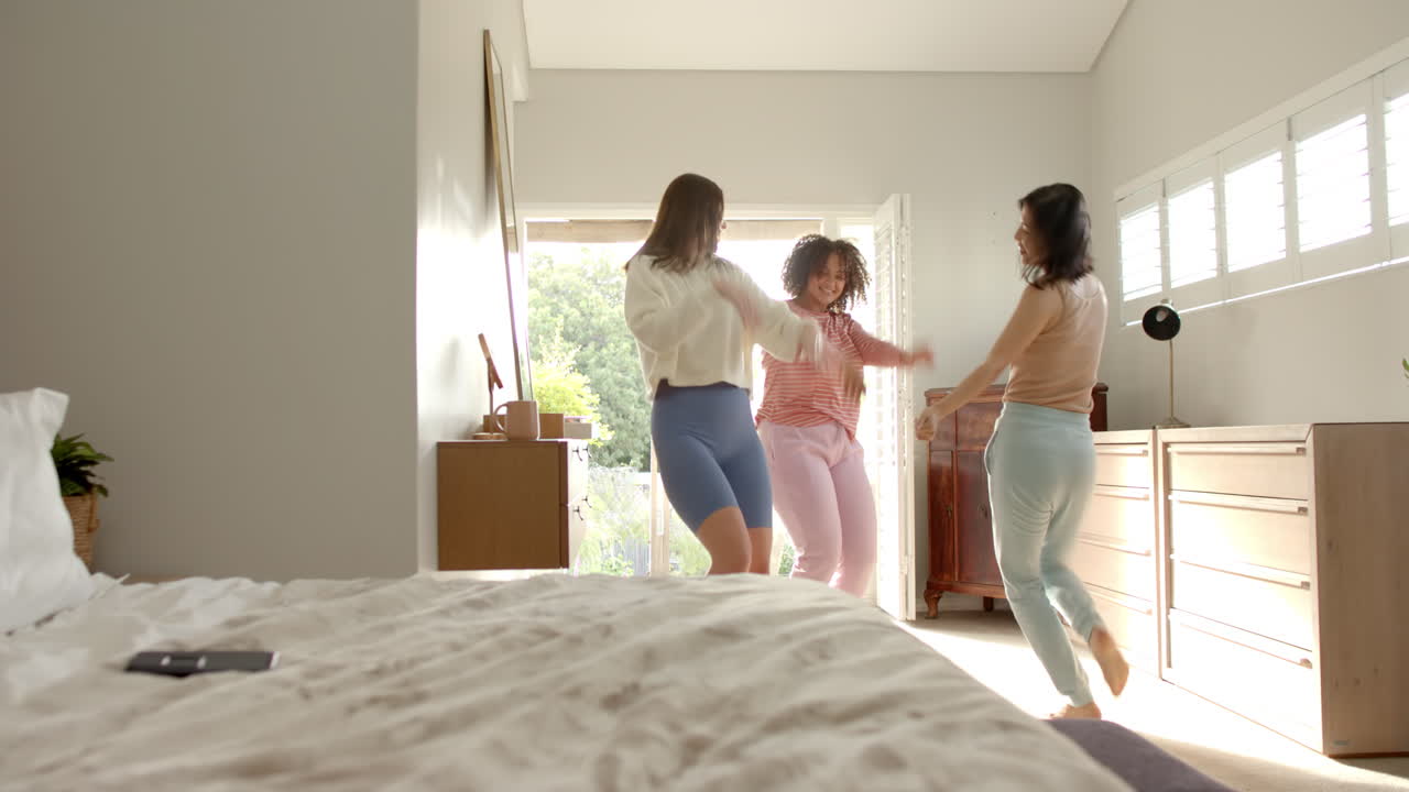 Dancing together, three diverse women friends enjoying time in bright room