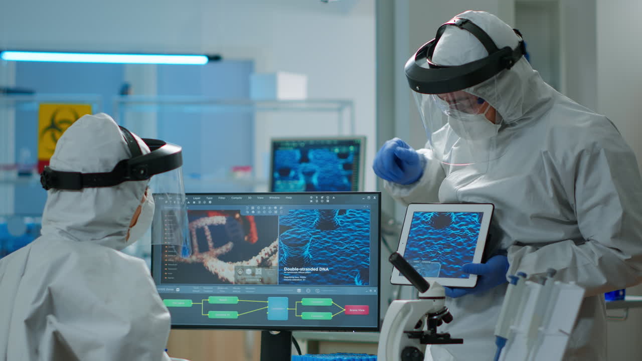 médicos en coveall discutiendo sobre el desarrollo del virus frente a la pc y la tableta